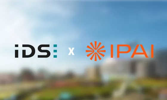 Los logotipos de IDS e IPAI aparecen uno junto al otro. Al fondo se ve el campus del IPAI.