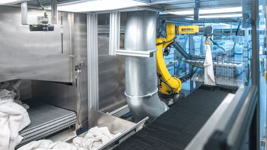 Un robot con sistema de cámaras 3D dobla toallas en una lavandería industrial