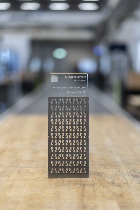 Premio TRUMPF Supplier Award al mejor innovador para IDS Imaging Development Systems GmbH: moderno galardón sobre una mesa de madera, símbolo de innovación.