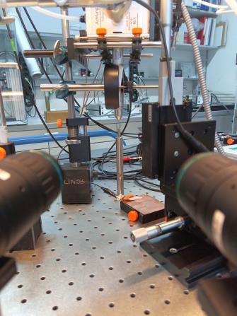 Montaje experimental sobre una mesa óptica con dos cámaras laterales y una fuente de plasma