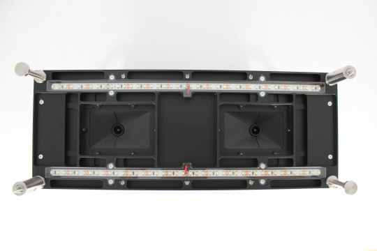 Parte inferior de un módulo negro con tiras LED, lentes y asas metálicas