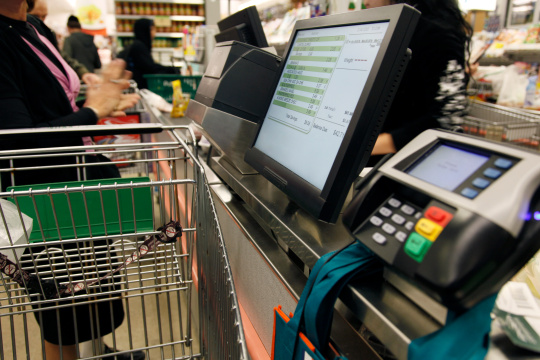 Mujer con carrito de la compra en una caja de autoservicio