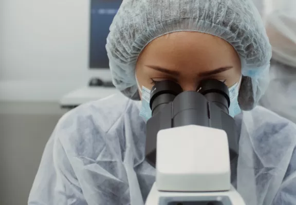 Una mujer mira por un microscopio en un laboratorio.