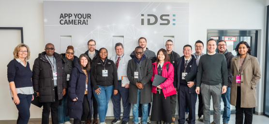 Delegación de 14 miembros del MIT REAP durante su visita a IDS delante de un muro de la empresa.
