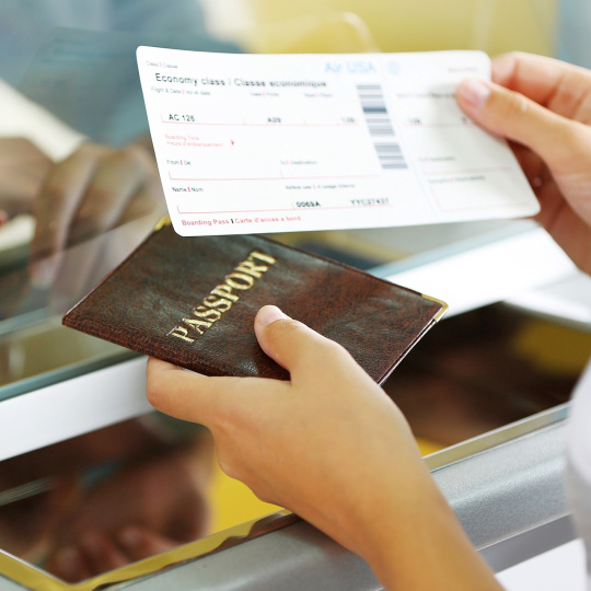 Una persona lleva un billete de avión y un pasaporte.