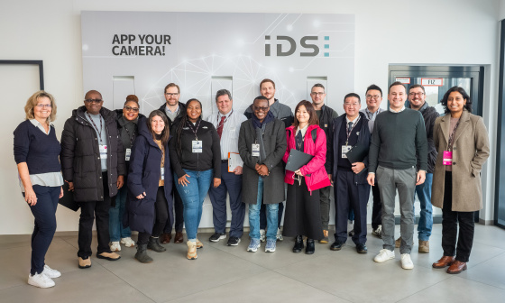 Delegación de 14 miembros del MIT REAP durante su visita a IDS delante de un muro de la empresa.