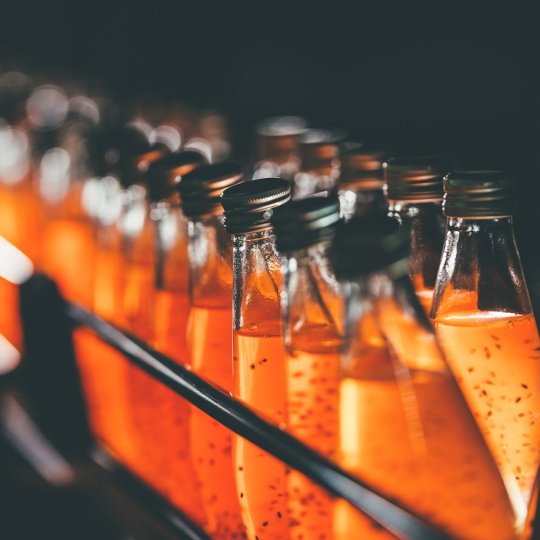 Botellas de vidrio en una estantería con líquido naranja.
