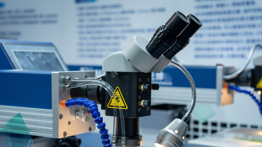 Microscopio binocular con tubos y lámpara en una instalación de laboratorio.