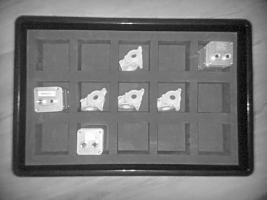 Imagen de intensidad en gris de la cámara 3D Nion que muestra diferentes objetos en una caja con bandejas de clasificación desde una vista superior.