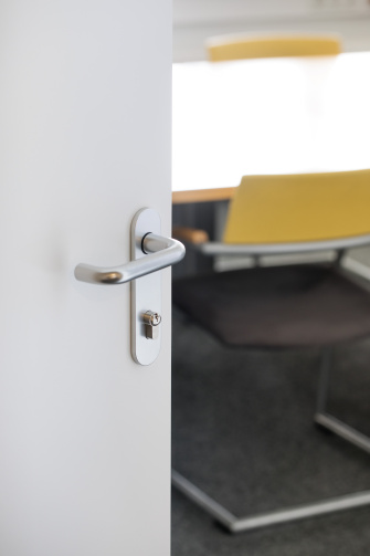 Puerta abierta con un tirador moderno y herrajes de control de acceso en el interior