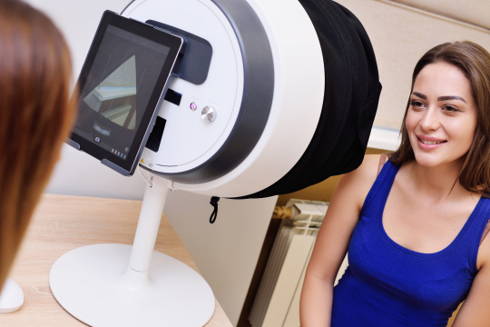 Mujer sentada frente a un aparato médico con una tableta en la parte posterior.